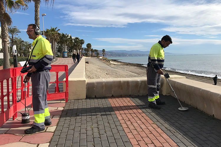 Two Hidralia operators look for leaks with helium gas on the seafront in Roquetas de Mar. One of them has a listening helmet and the other device to find water under the ground.
