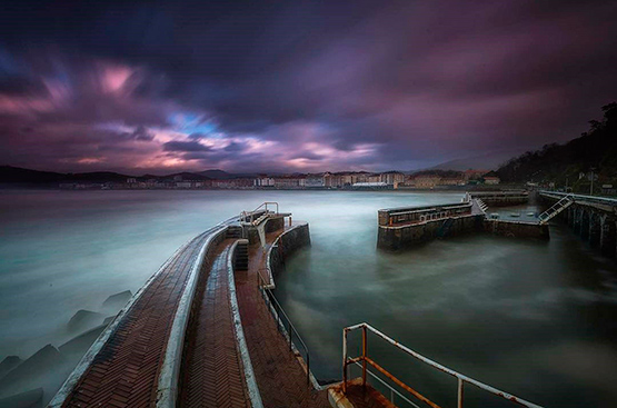 Winning image of the PhotoAquae Award in 2018. It is the photograph of a fishing port amidst fog and blurred, without boats, where gray and purple colors dominate.