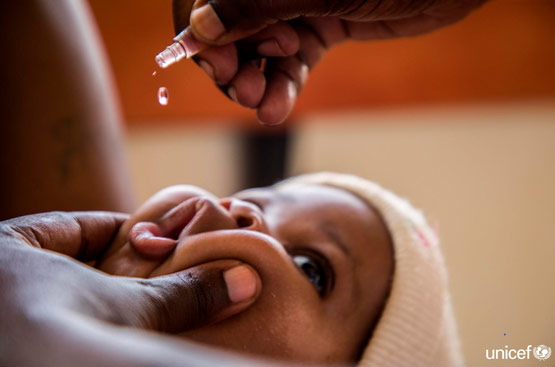A person gives a baby a drinkable vaccine.